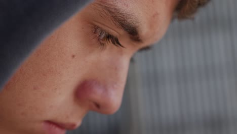 closeup side shot of the face of a young teen boy sitting in a garage alone looking sad and depressed