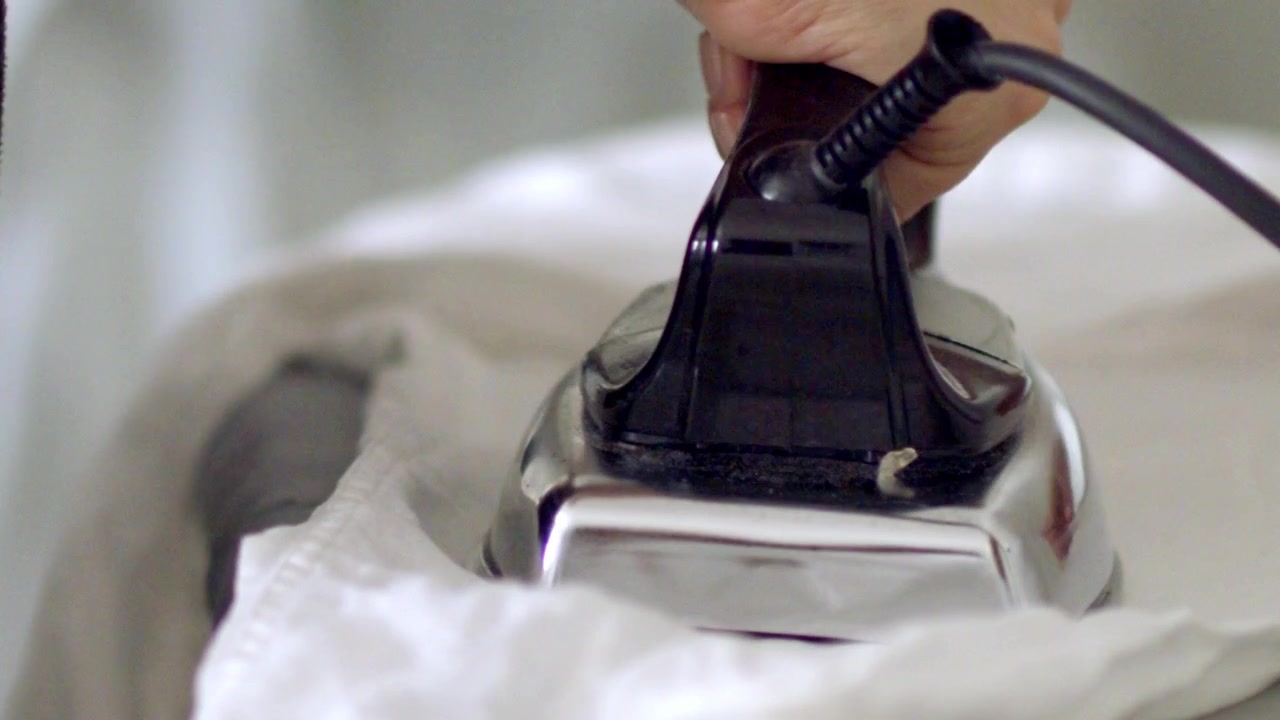 Domestic clothes chores, white linen material care, slow motion view
