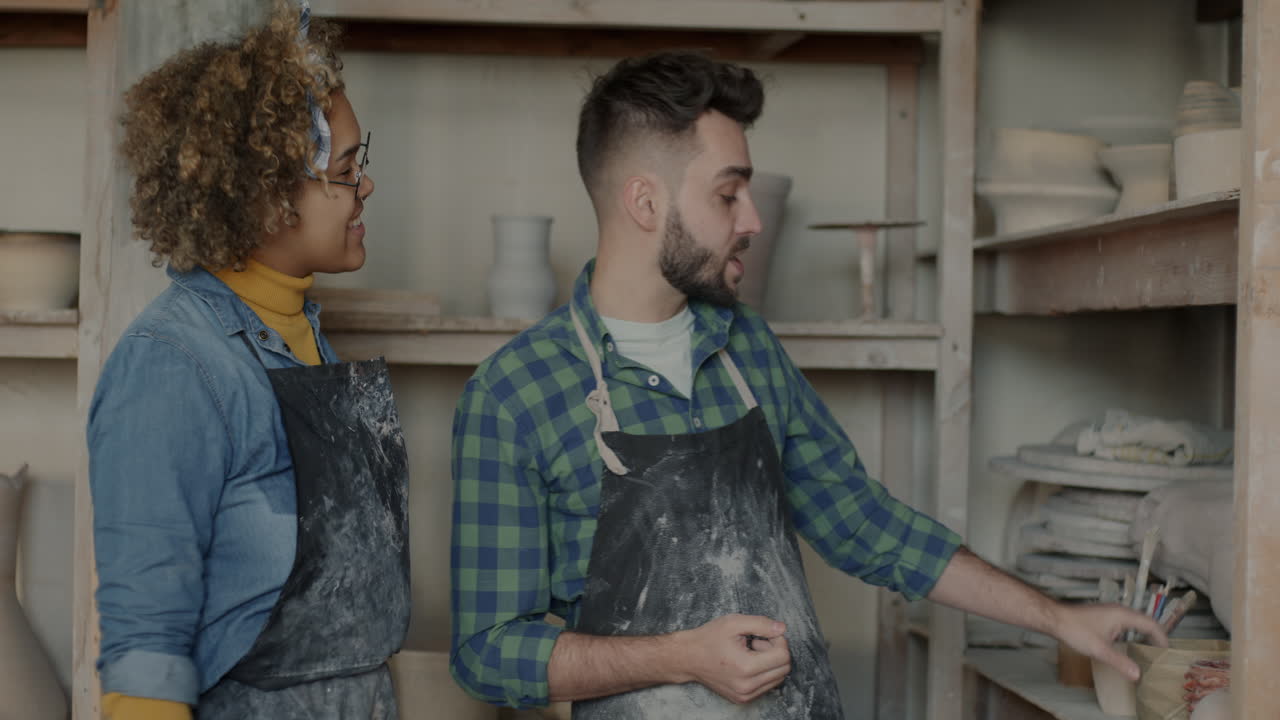 Two artisans discussing pottery design in a workshop