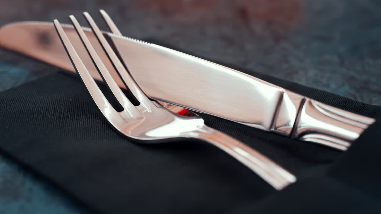 Close up of silver cutlery placed neatly on a dark napkin at a restaurant