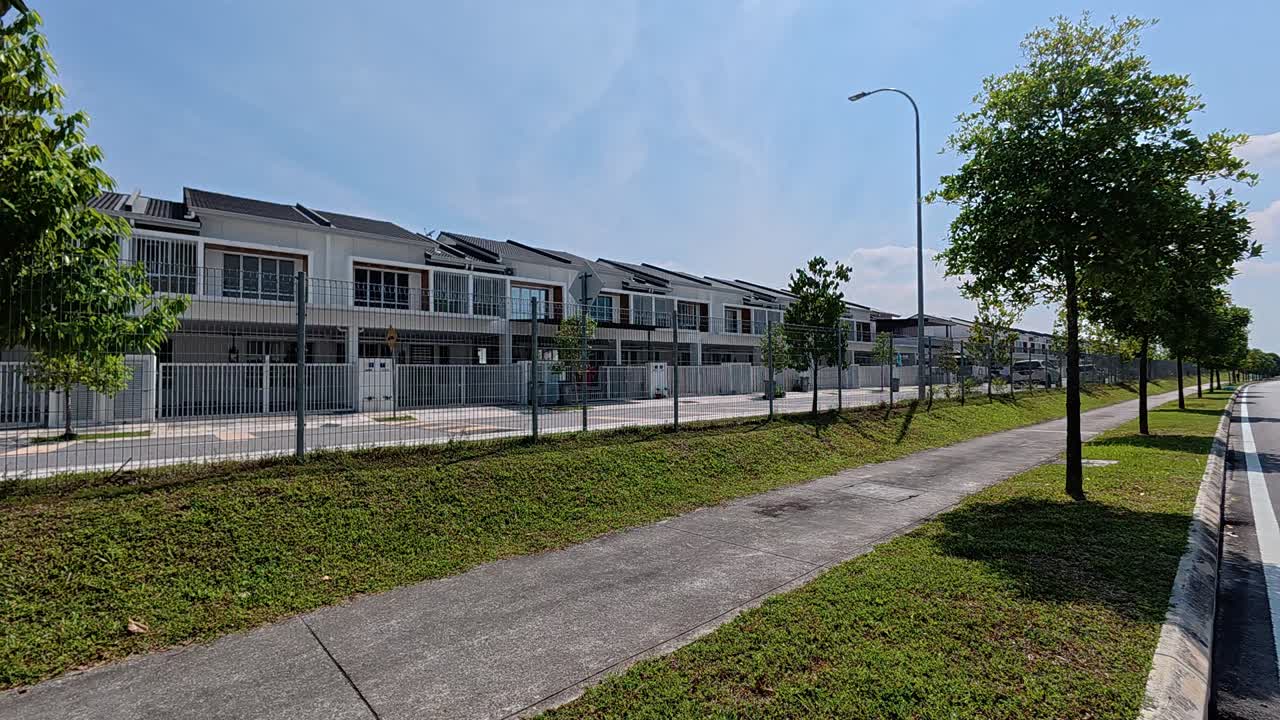 A modern terraced housing area in Malaysia with clean, green landscaping. The gated community features a variety of essential amenities and is free of trash