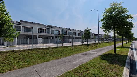 a modern terraced housing area in malaysia with clean, green landscaping. the gated community features a variety of essential amenities and is free of trash
