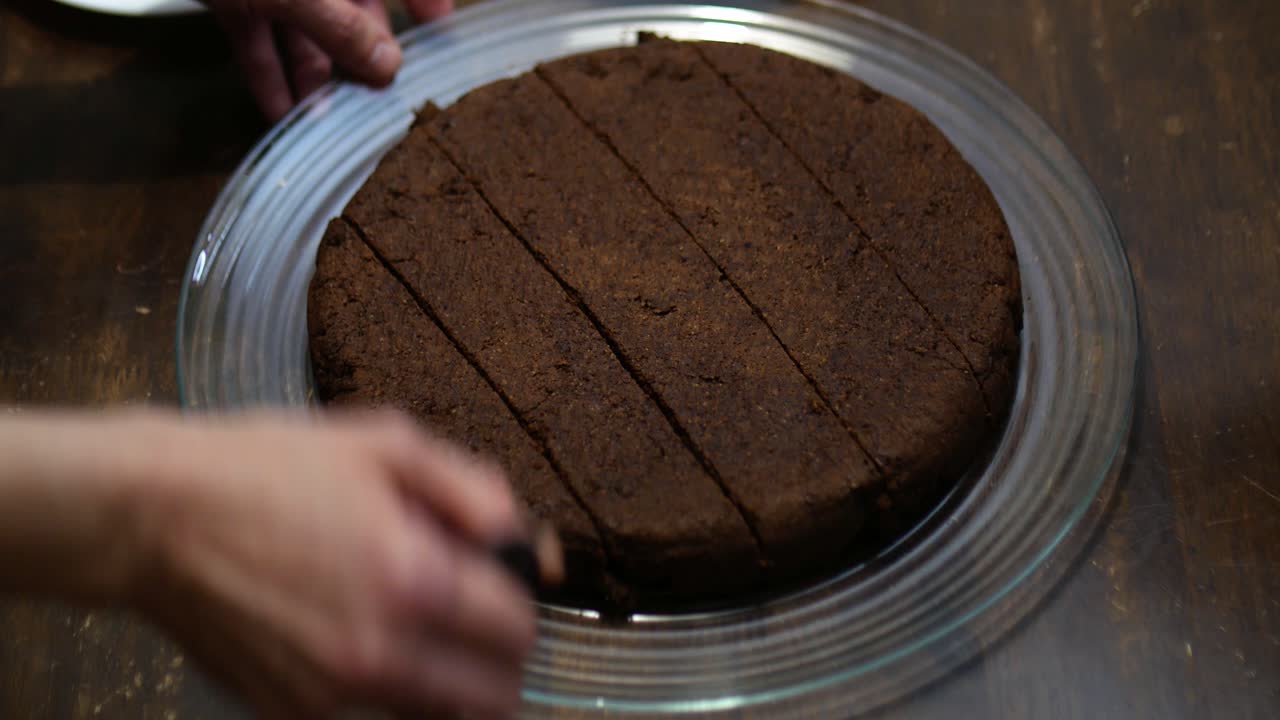 lapso de tiempo de manos cortando un pastel de brownie de chocolate keto en trozos pequeños