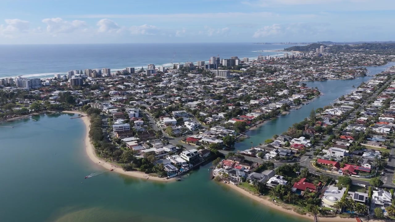 Vista aérea frontal con paneo hacia la derecha sobre Tallebudgera Creek, Palm Beach y los barrios costeros circundantes en la Costa Dorada, Queensland, Australia.