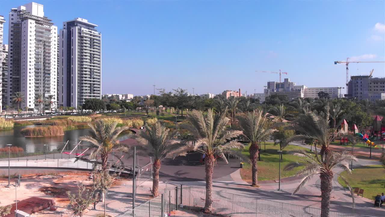 Urban Park with Modern Buildings and Palm Trees by a Lake