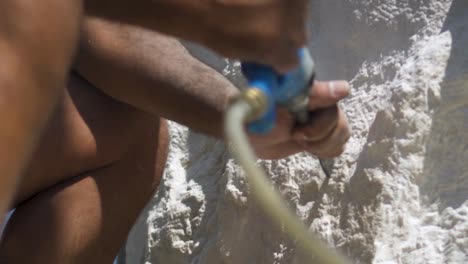 sculptor with pneumatic hammer roughly carve white stone in sunny day - close outdoor shot