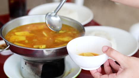 ladling soup into bowls at a dining table