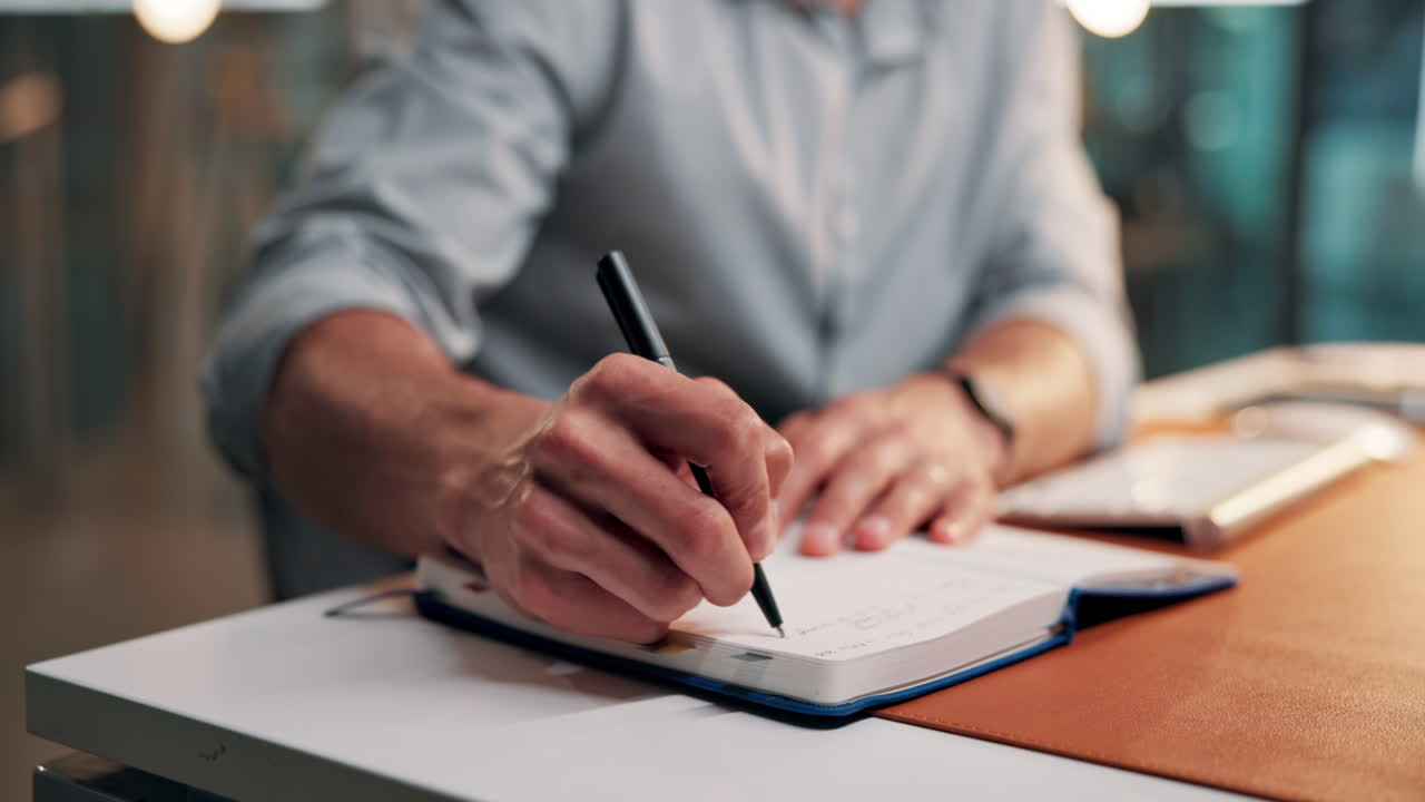 Close-up of a Person Writing Notes in a Notebook at a Desk