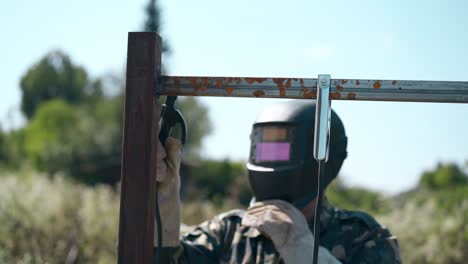 man in protective mask and gloves fixes plank to fence top