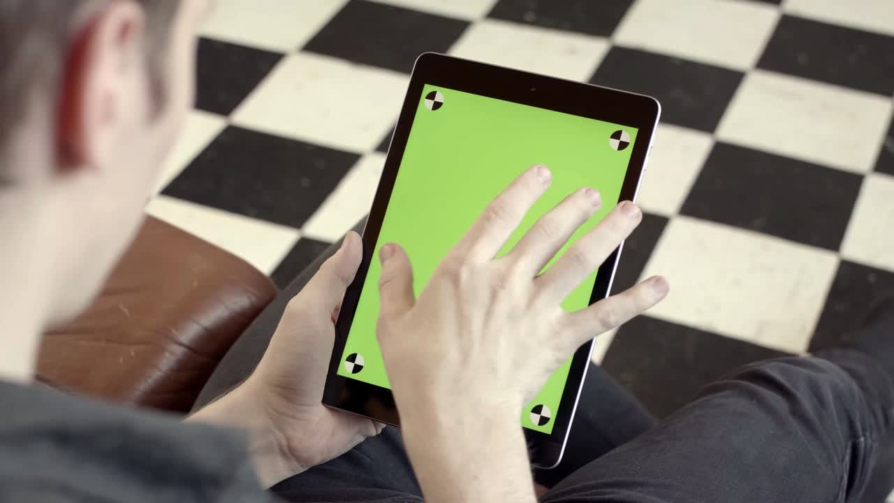 녹색 화면을 가진 태블릿을 사용하는 사람