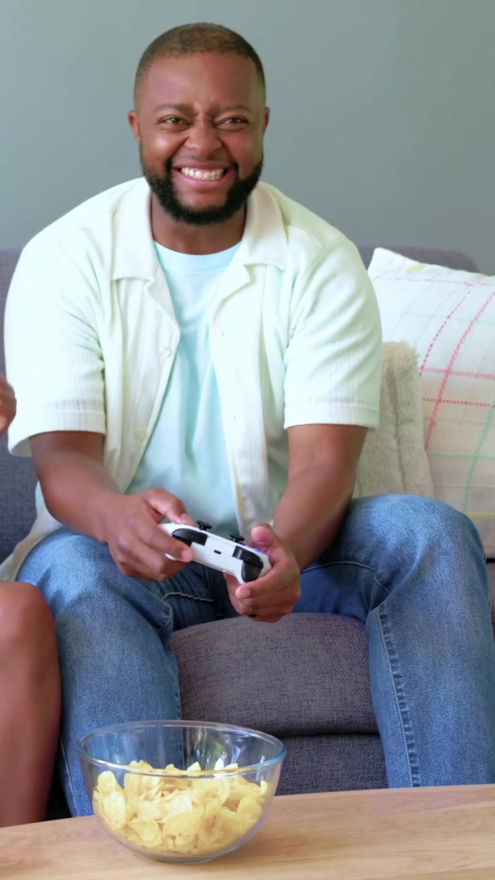 Vertical video: Game starting, man playing controller with child on couch at home for fun