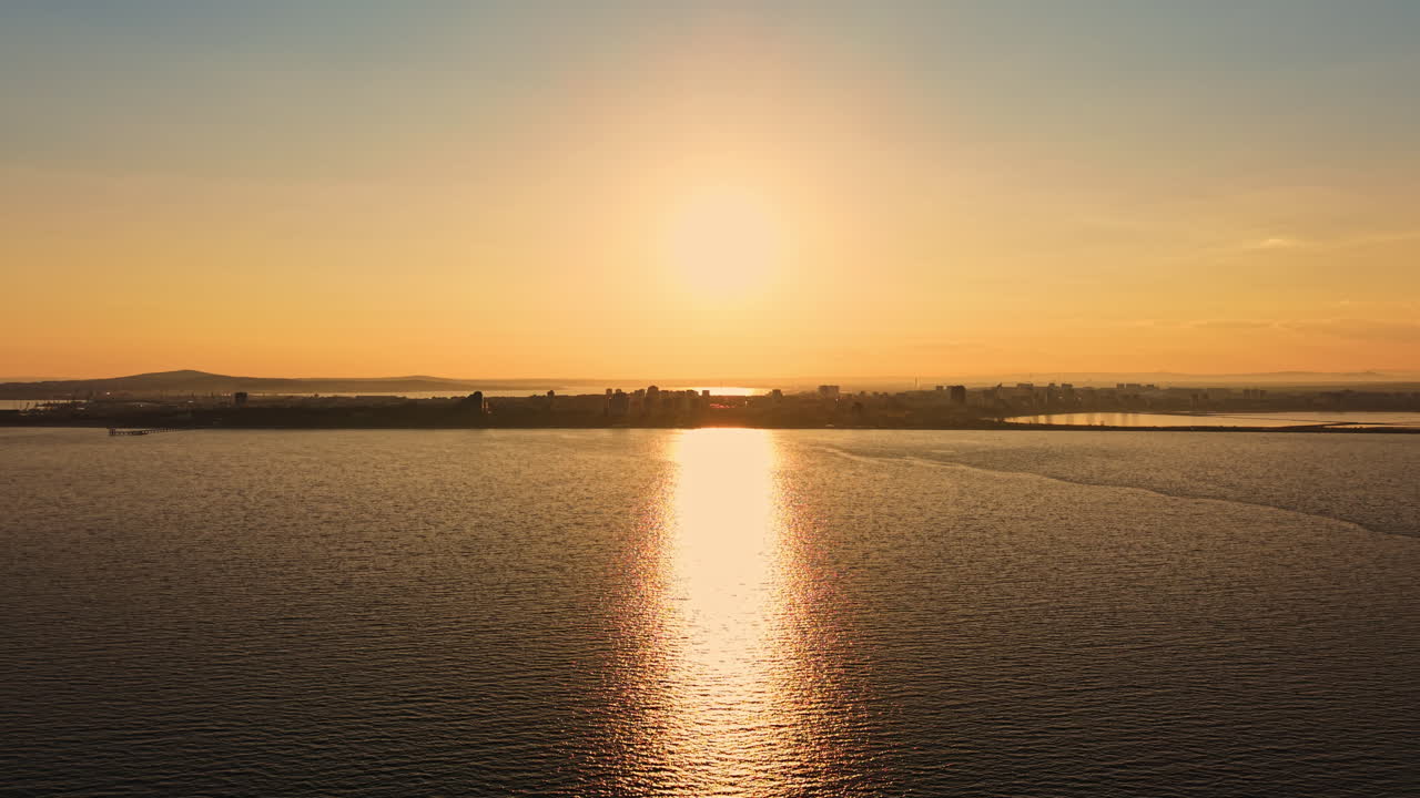 Sunset over the water showing reflection and city skyline in the background during evening hours