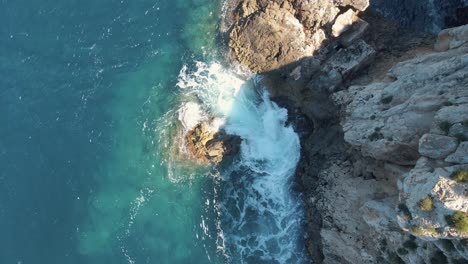 Luftaufnahme-Von-Türkisfarbenem-Meerwasser,-Das-Auf-Felsen-Auf-Der-Mexikanischen-Insel-Cala-Llonga-Trifft