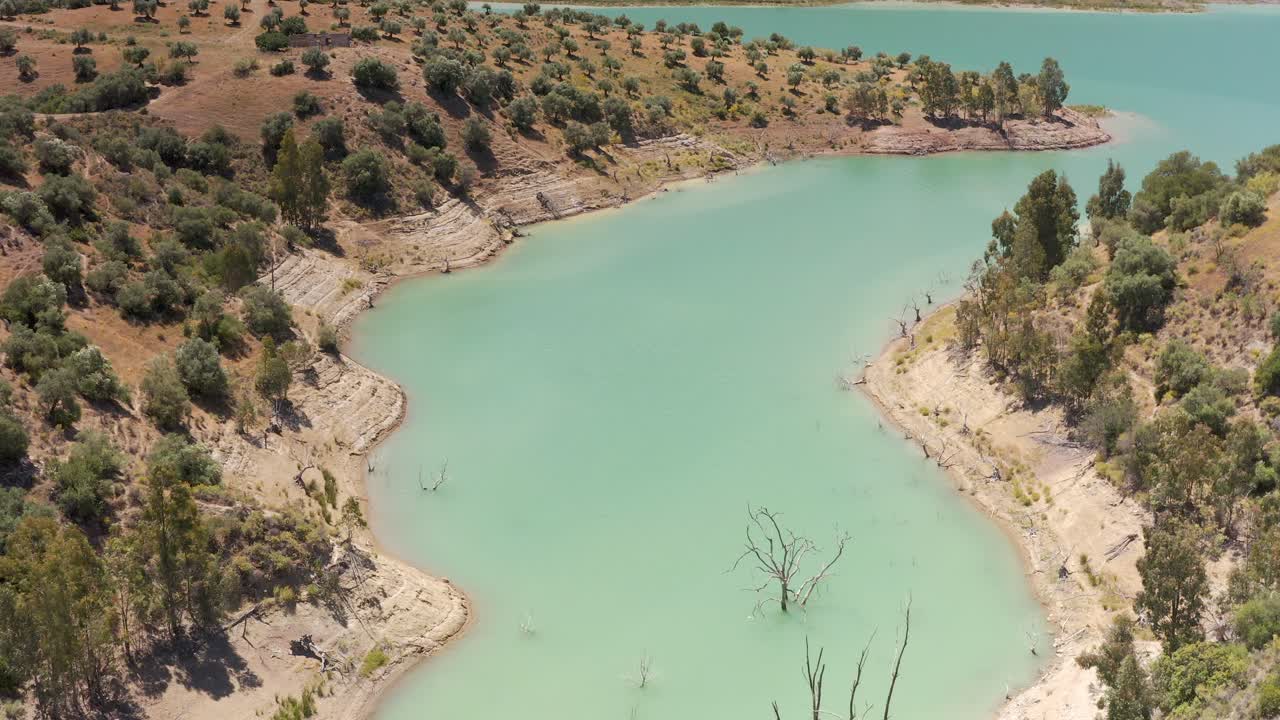 언덕 과 나무 들 이 있는 티르코이스색 저수지 의 공중 사진