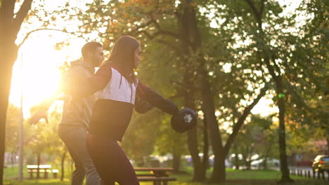 couple exercising with dumbbells in park