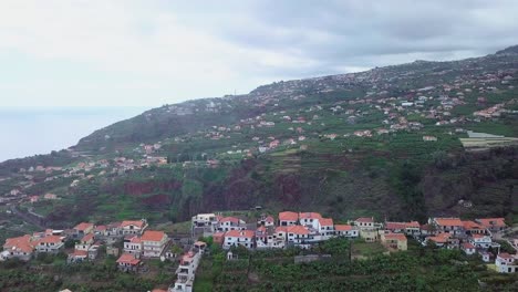 drone flying over the lush volcanic island of madeira in portugal, well-developed and filled with residential houses - aerial