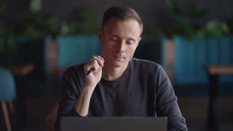 thoughtful serious young man student writer sit at home office desk with laptop thinking of inspiration search problem solution ideas lost in thoughts concept dreaming looking away