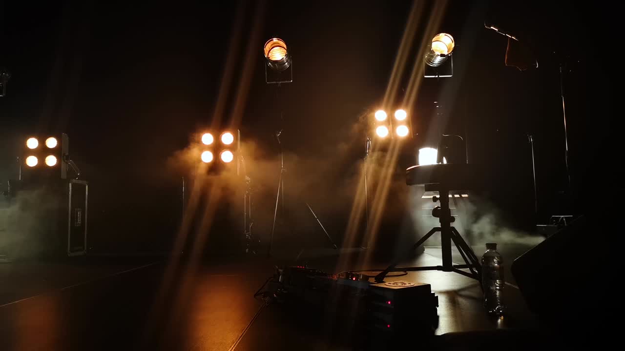 Close-up video of a concert stage and lighting fixtures on it. smoke from a smoke installation gently breaks yellow light and creates the effect of a gentle glow.