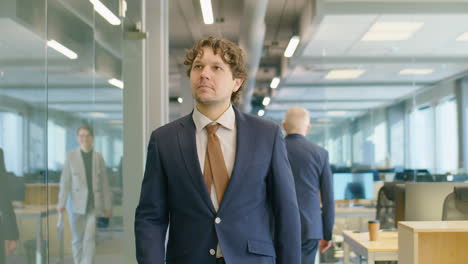 businessman walking in office and greeting colleague