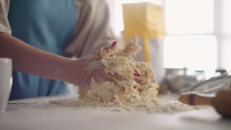 woman is kneading dough in table in home kitchen, cooking pizza for family for breakfast, closeup of hands