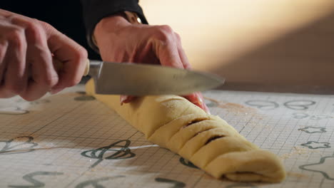 hands cutting rolled up dough with filling for cinnamon rolls. closeup shot