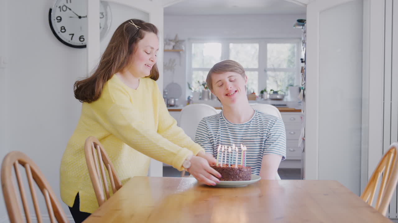 다운 증후군의 젊은 부부가 케이크와 함께 집에서 생일을 축하합니다.