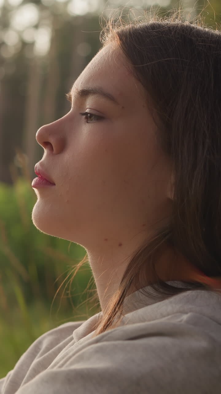 Tired woman leans against tree in forest at sunset. Young lady feels negative emotions after hard breakup finding solace from stress in nature