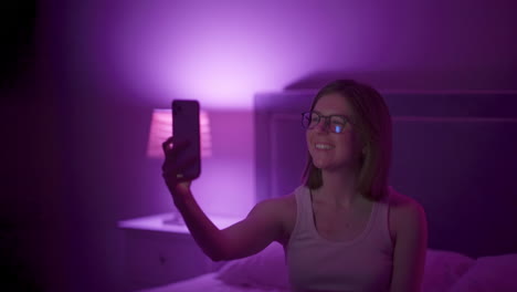 girl sits on bed late at night taking selfies with flash off