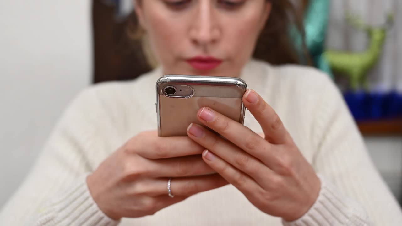 Close up of a brunette woman in a white turtleneck scrolling through her phone