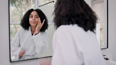 woman applying skincare in bathroom mirror