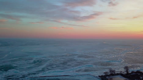 Pink,-orange-and-yellow-sunset-over-frozen-lake-Erie-in-Canada-during-winter