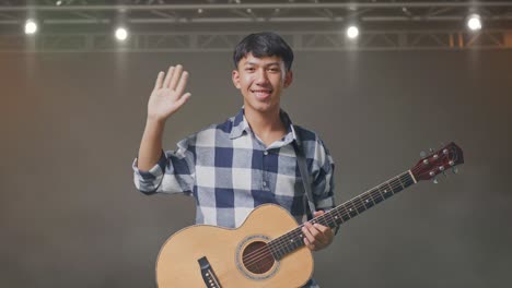 기타를 흔들고 무대에서 카메라를 향해 미소 짓는 아시아 십대
