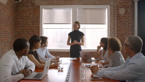 businesswoman standing to address boardroom meeting