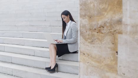 mujer sonriente usando una laptop en las escaleras