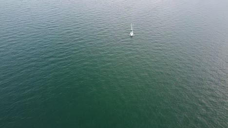 static drone shot of sailboat crossing the frame