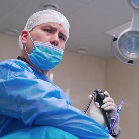 portrait of a surgeon during operation. serious male specialist in blue mask performing a surgery in the modern operating room in clinic.