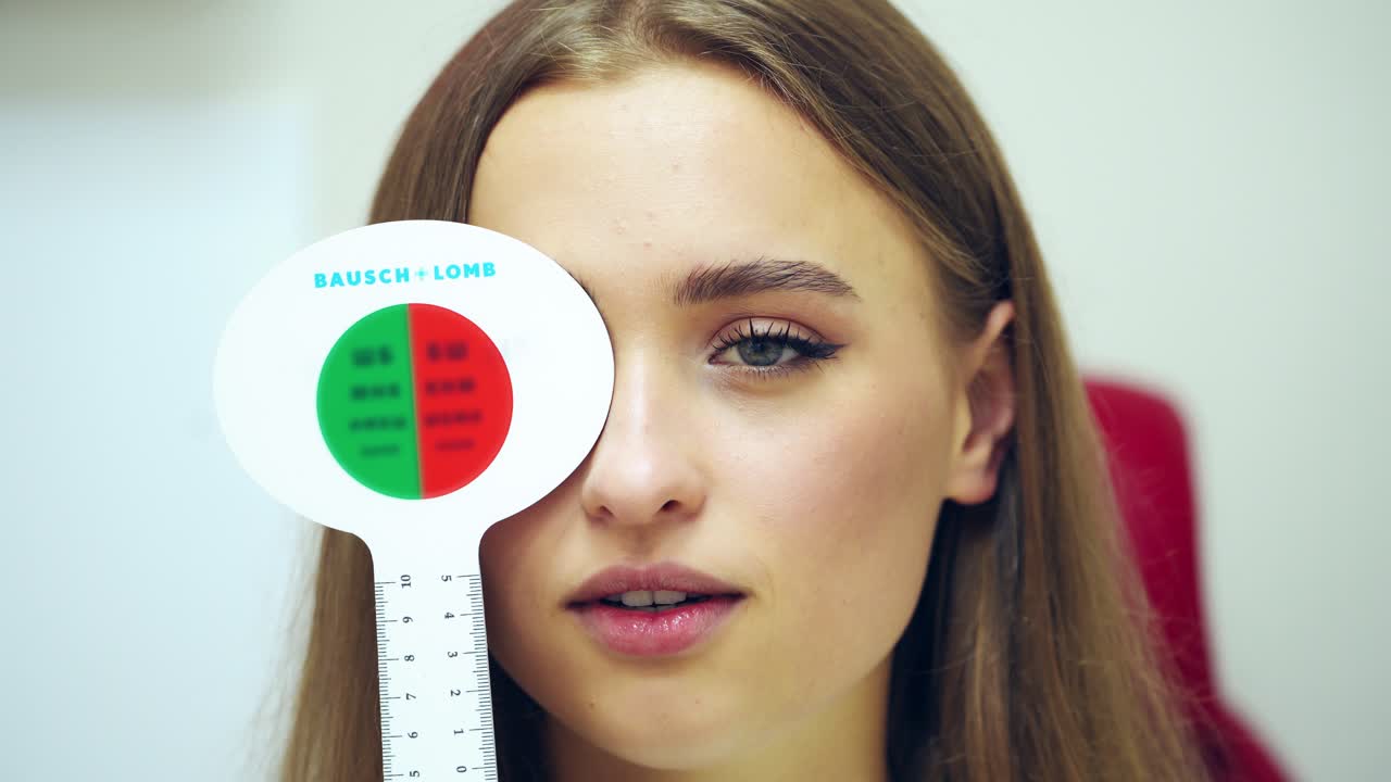 Woman having eye exam. Beautiful girl checks vision at ophthalmologist with one eye closed