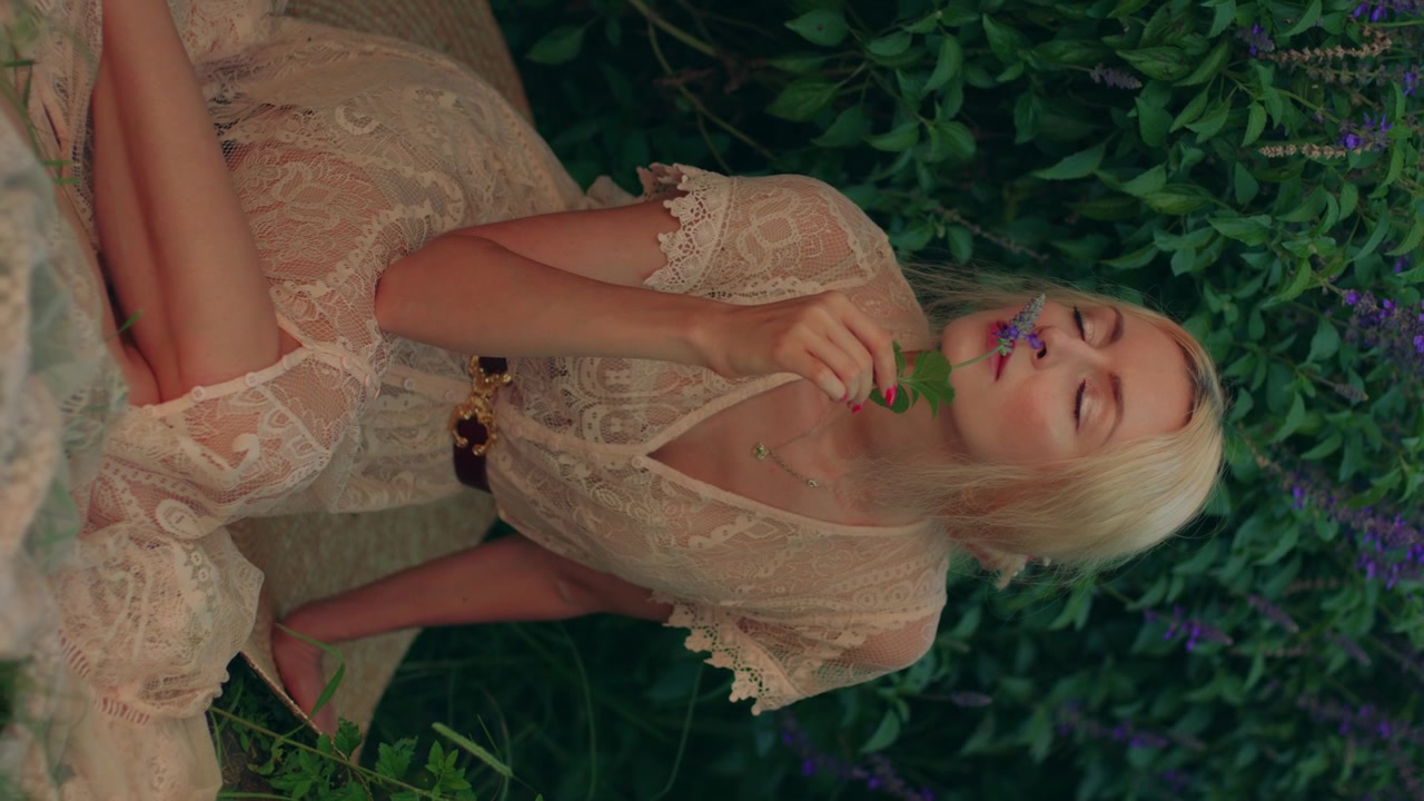 Young Woman in Lace Dress Relaxing in Garden with Flowers