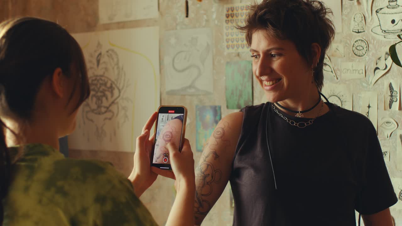 Woman Posing with New Tattoo for Female Artist Taking Photos with Phone
