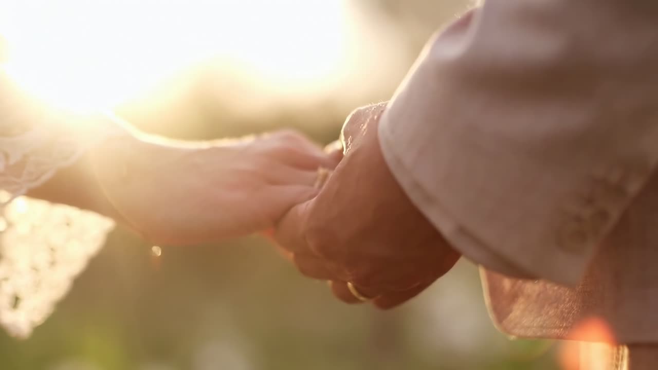 Primo piano video di una coppia che si tiene per mano, ripreso con un'angolazione romantica e dal basso.