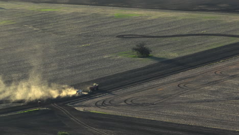 drone shot of a tractor ploughing in a dusty field late in the day neat moree, new south wales, australia