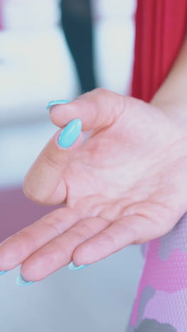 relaxed woman hand with manicure holds fingers in guan mudra position lying on knee in hammock extreme close view