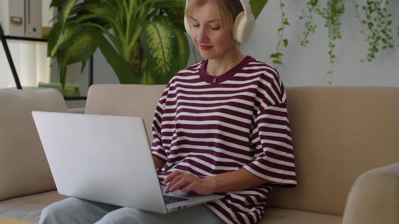 Female Entrepreneur Listening to Music in Headphones when Working on Laptop