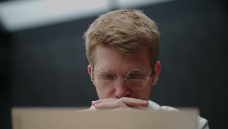 authentic portrait of young confident businessman looking at screen with laptop in office. hipster man in glasses