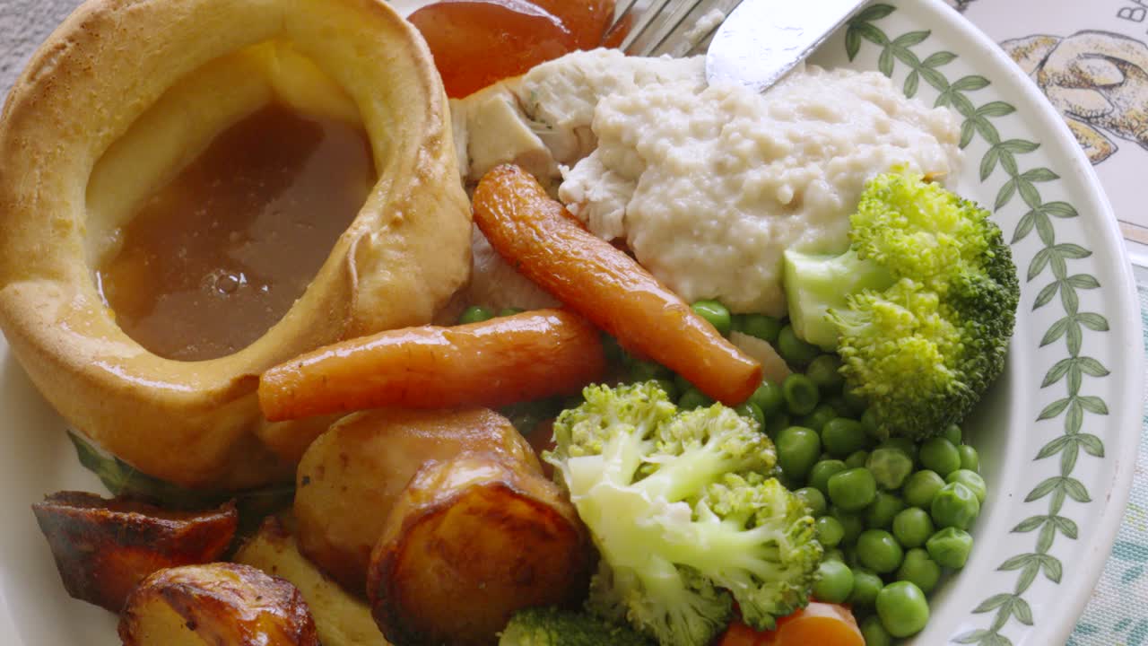 Vista dall'alto di un arrosto britannico con Yorkshire Puddings, carote, broccoli, piselli e salsa al pane. 4K