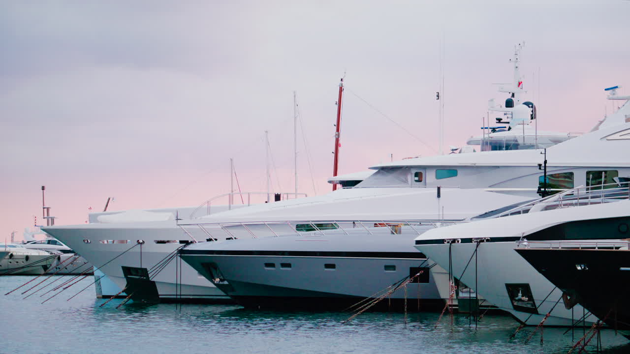 Three luxury yachts docked side by side in a calm marina, captured in soft daylight
