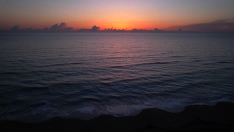 Vista-Aérea-Estática-Del-Amanecer-En-La-Playa-De-Las-Olas-Rodando-En-La-Arena