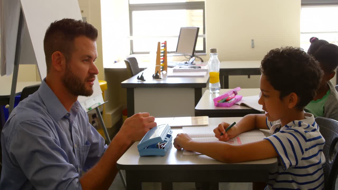escolar caucásico estudiando con un maestro de escuela masculino en el aula de la escuela 4k