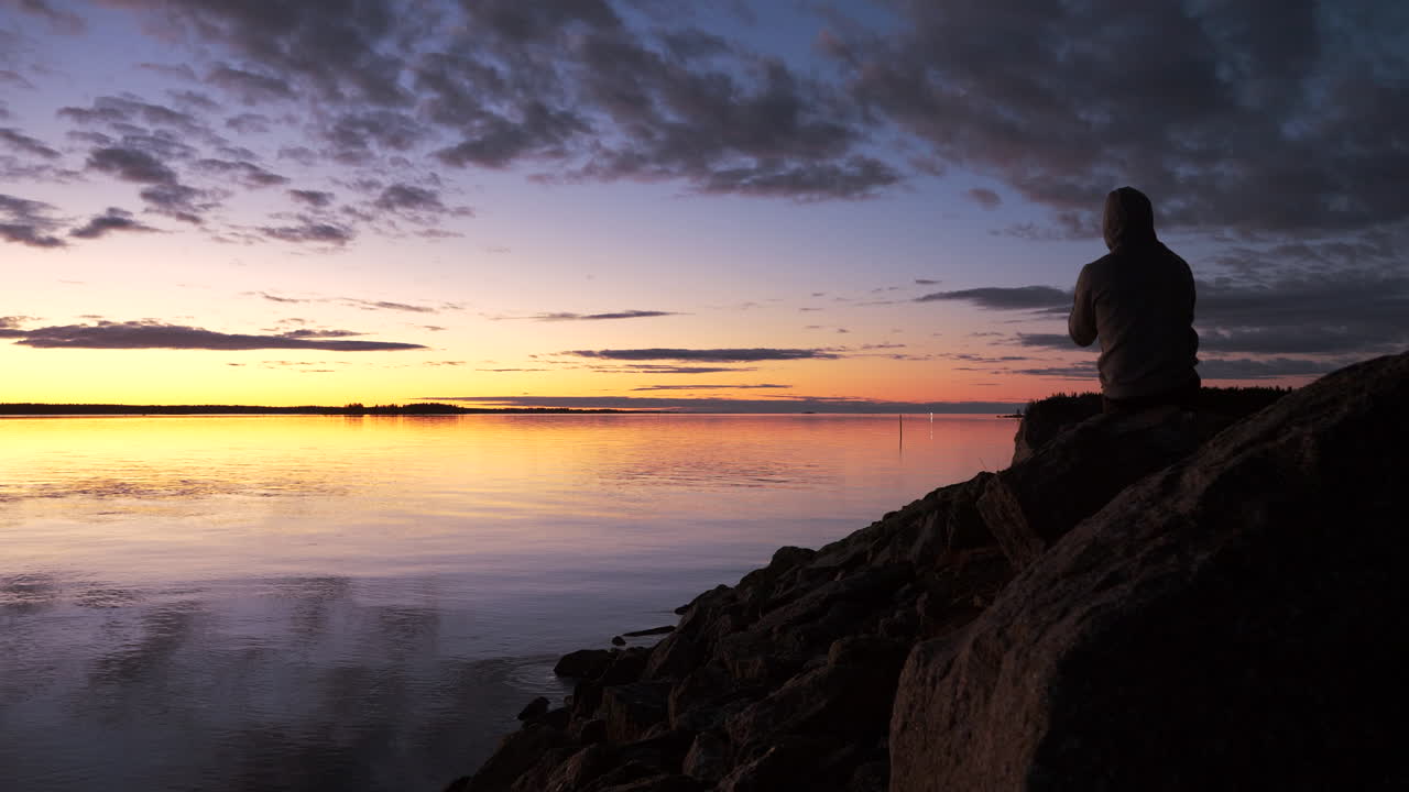 silueta de hombre tomando fotos telefónicas de la vívida puesta de sol del océano