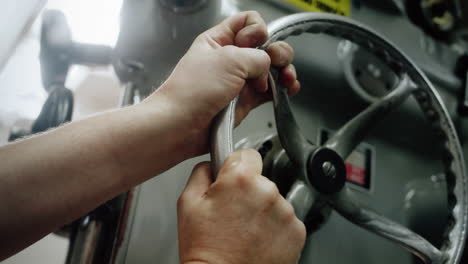 Close-up-of-the-hands-of-a-factory-worker-operating-a-big-metal-drilling-machine-in-slow-motion